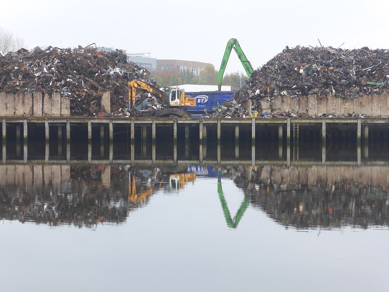 Ferrous scrap piles being sorted by material handlers at a scrap yard